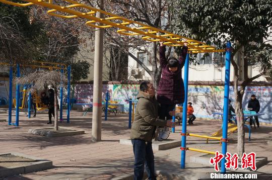 阳光下，一位父亲陪着女儿玩得十分开心。　韩章云 摄